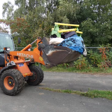 Ein Radlader hat in seiner Schaufel Müll, der weggefahren wird.